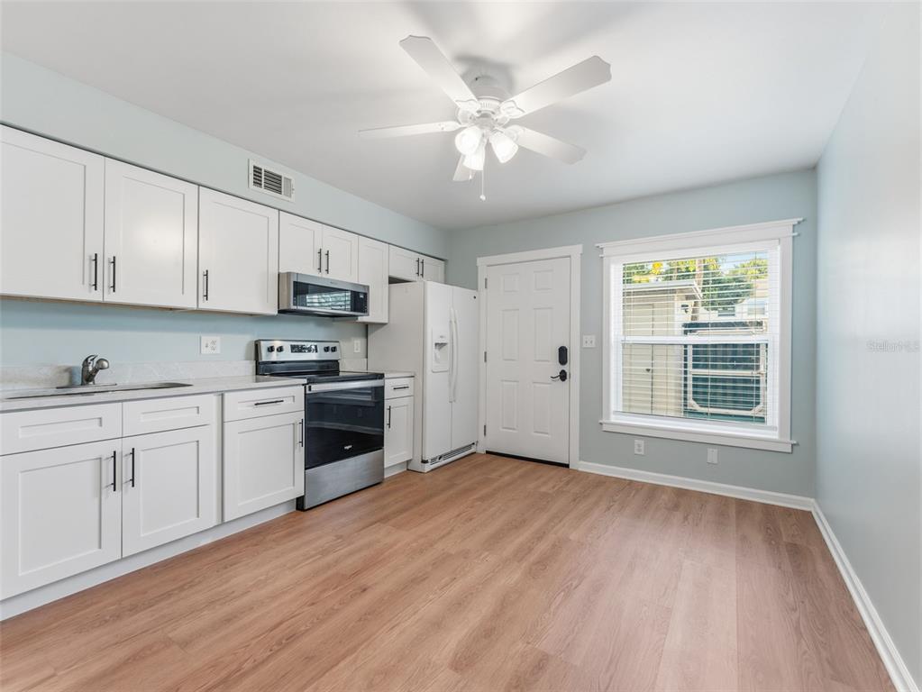 A kitchen with white cabinets, stainless steel appliances, light wood flooring, and a ceiling fan — 4233 LA SORRENTO COURT, TAMPA, FL