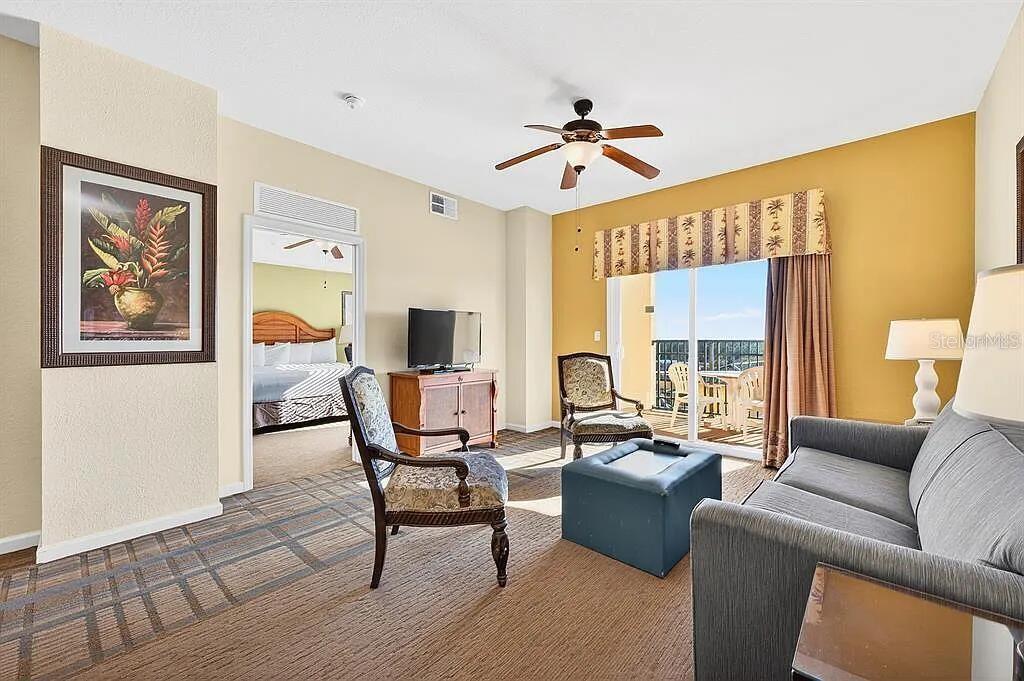 A living room with a sofa, chairs, and a doorway leading to a bedroom — 8101 RESORT VILLAGE DRIVE UNIT 3401, ORLANDO, FL