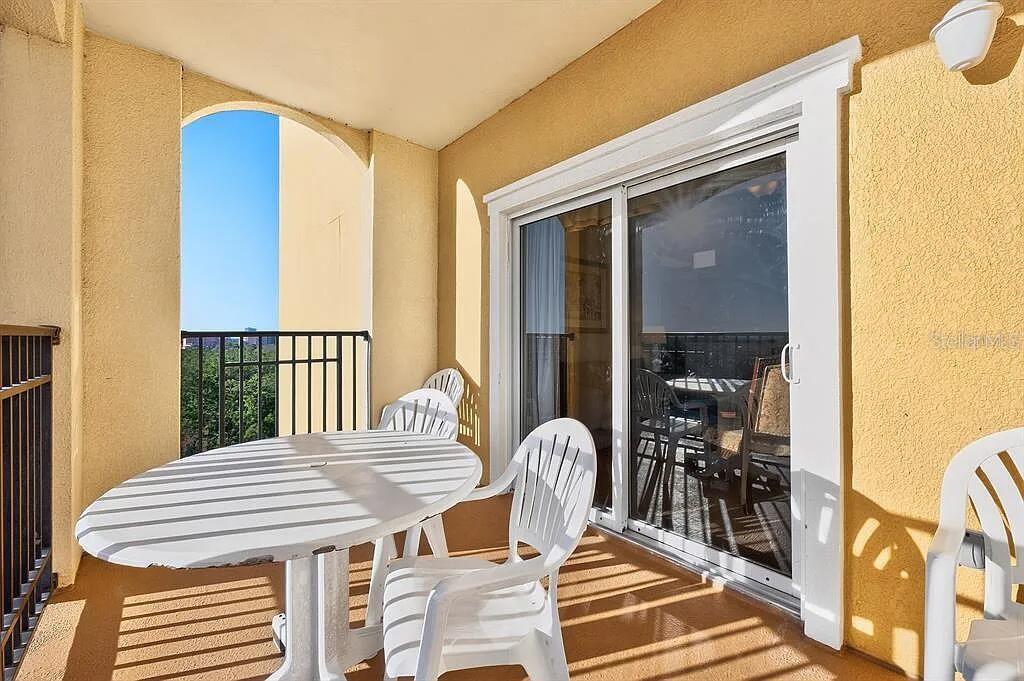 A balcony with a white table and chairs sits outside a sliding glass door — 8101 RESORT VILLAGE DRIVE UNIT 3401, ORLANDO, FL