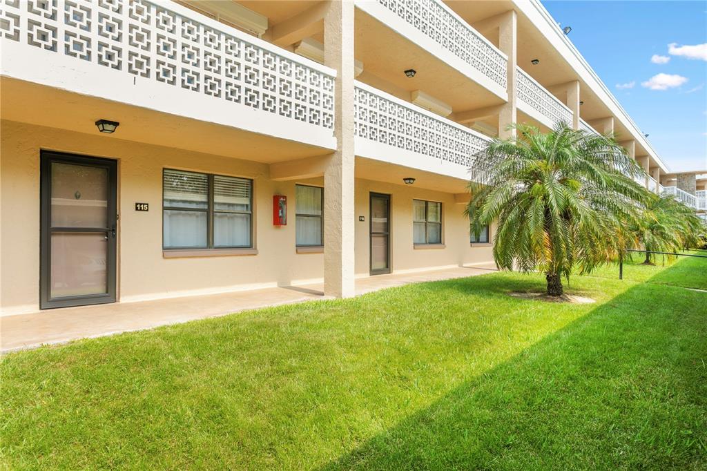 A multi-story apartment building features exterior walkways with decorative railings and a palm tree — 4920 LOCUST STREET NE UNIT 115, ST PETERSBURG, FL