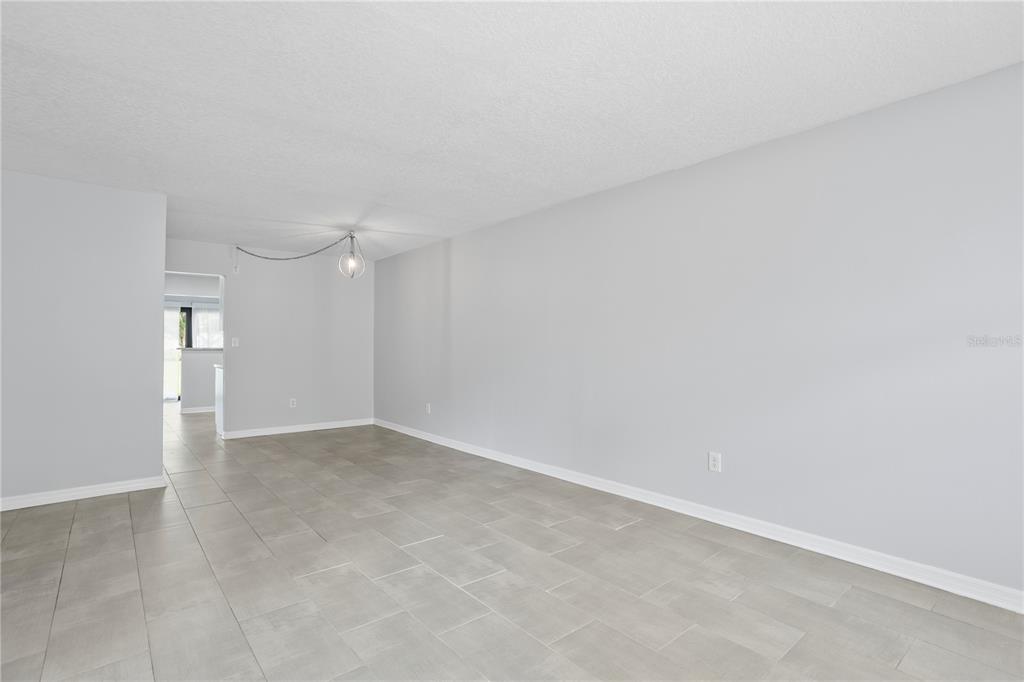 An empty room with light gray walls, tile flooring, and a single hanging light fixture — 4920 LOCUST STREET NE UNIT 115, ST PETERSBURG, FL