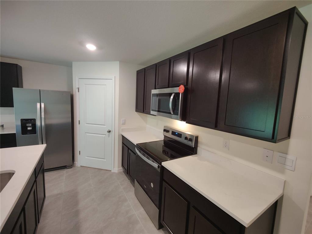 A kitchen features dark wood cabinets, stainless steel appliances, and white countertops — 11284 SE 67TH CIRCLE, BELLEVIEW, FL