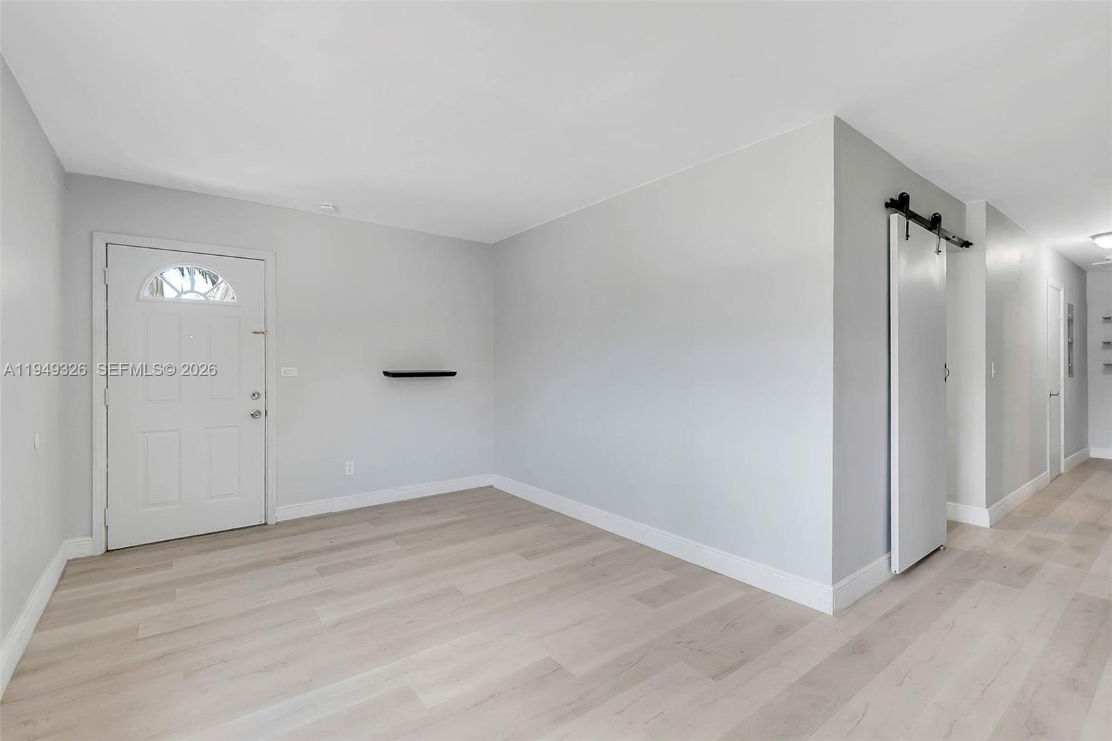 This room features light gray walls, light wood-look flooring, a white front door, and a shelf — 9710 SW SW 161 ST, Miami FL 33157, MIAMI, FL