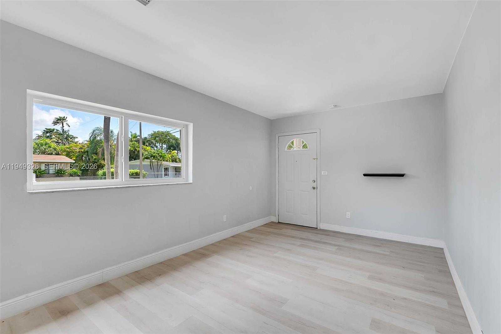 A room with light gray walls, light wood-look flooring, a window, and a white door — 9710 SW SW 161 ST, Miami FL 33157, MIAMI, FL