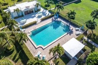 An aerial view shows a swimming pool, a patio, and a house surrounded by palm trees — 100 Waterway Rd # A306, Tequesta FL 33469, TEQUESTA, FL