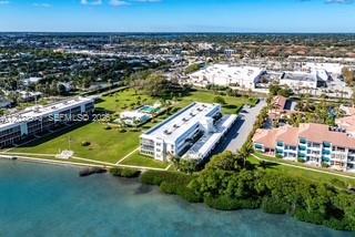 An aerial view shows multi-story waterfront apartment buildings surrounded by green space and mangroves — 100 Waterway Rd # A306, Tequesta FL 33469, TEQUESTA, FL