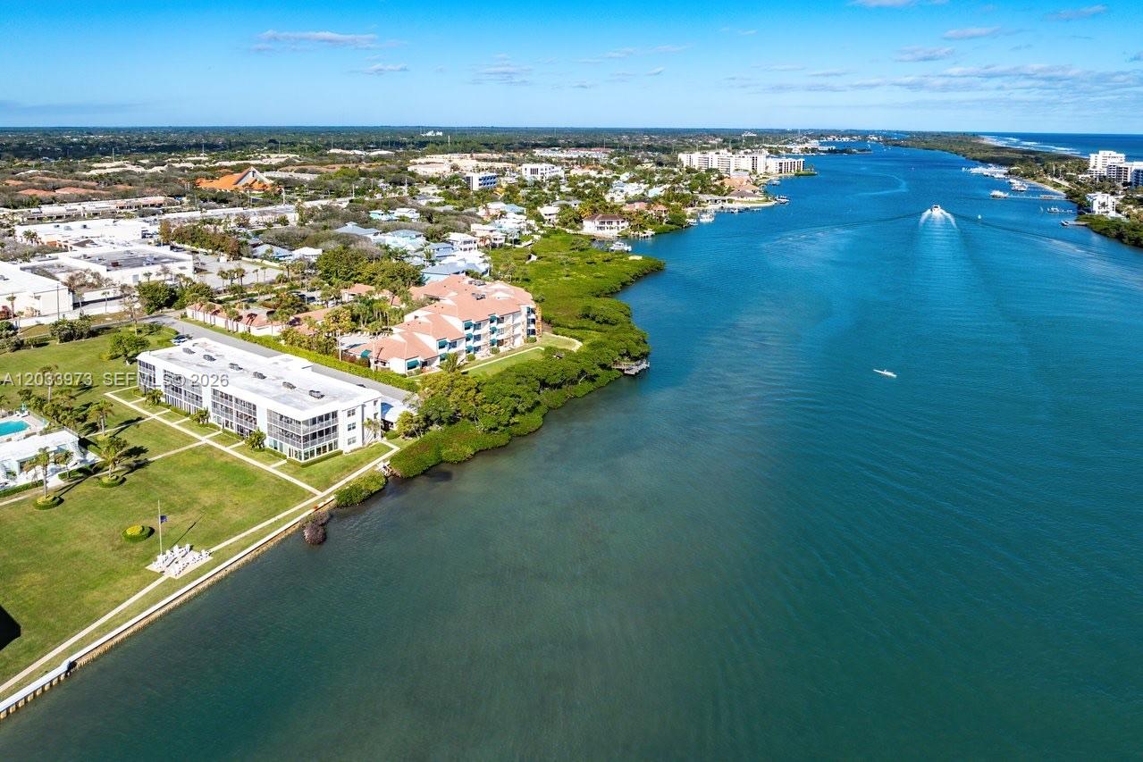 An aerial view shows a waterfront apartment complex with a lawn beside a river — 100 Waterway Rd # A306, Tequesta FL 33469, TEQUESTA, FL