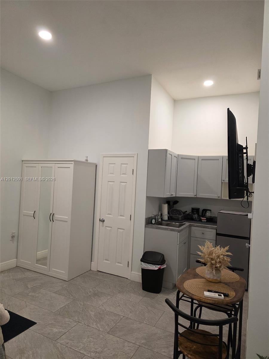 A small kitchenette with gray cabinets sits next to a white wardrobe and dining table — HOMESTEAD, FL
