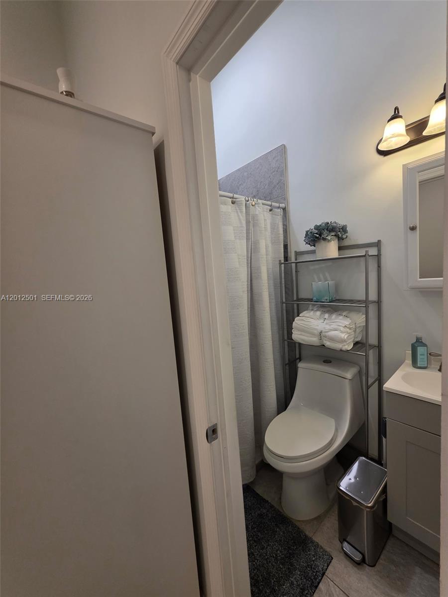 A small bathroom features a toilet, a metal storage rack, and a vanity — HOMESTEAD, FL