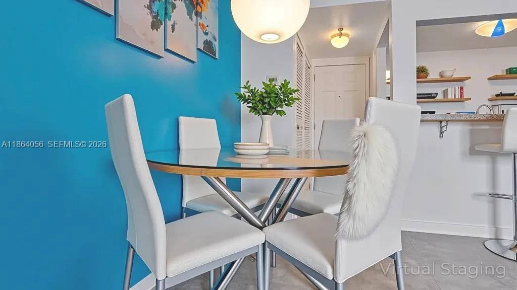 A dining area features a round wooden table, four upholstered chairs, and a blue accent wall — 865 Collins Ave # 207, Miami Beach FL 33139, MIAMI BEACH, FL