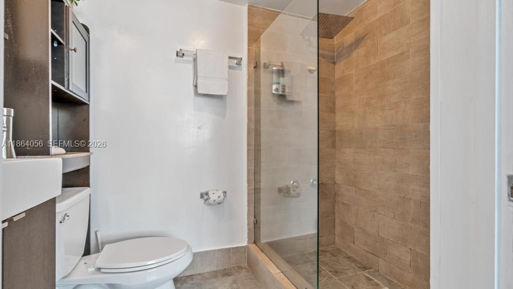 A kitchen pass-through window features a granite breakfast bar with two stools and open shelving — 865 Collins Ave # 207, Miami Beach FL 33139, MIAMI BEACH, FL