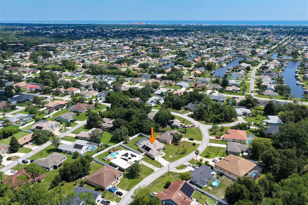 An aerial view of a suburban neighborhood with an orange arrow pointing to a house — 62 FORRESTER PLACE, PALM COAST, FL
