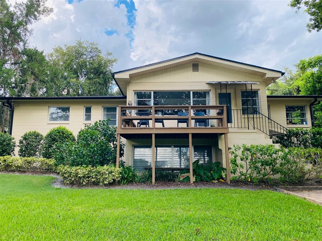 A two-story house with a wooden deck, light-colored siding, and a green lawn — 1113 VIA DEL MAR, WINTER PARK, FL
