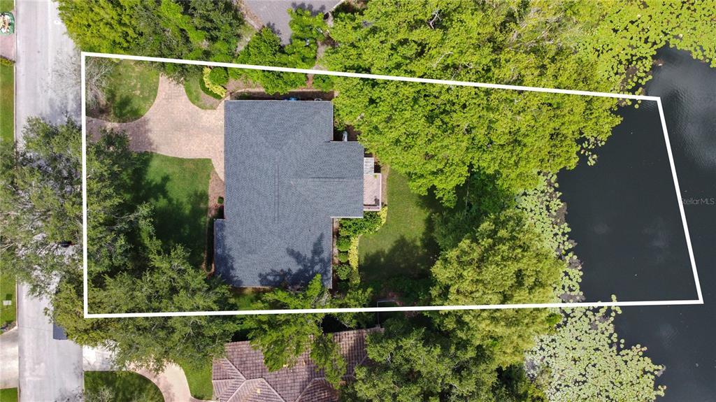 An aerial view shows a house with a dark roof situated on a wooded lot — 1113 VIA DEL MAR, WINTER PARK, FL