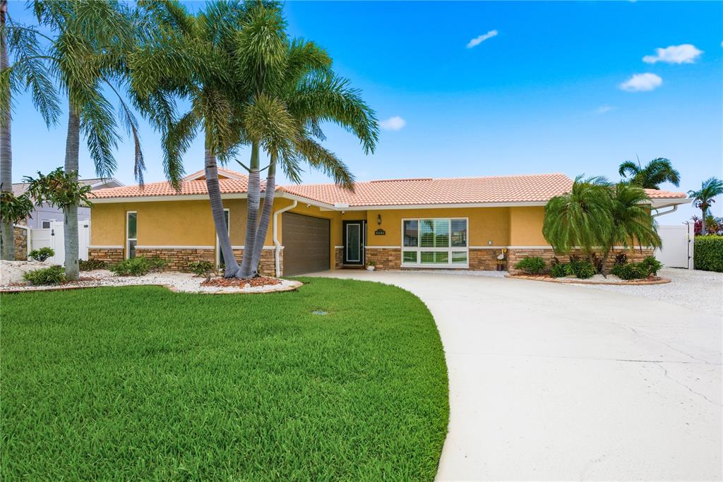 A single-story house with a yellow exterior, stone accents, and a tile roof — 5351 PILOTS PLACE, NEW PORT RICHEY, FL