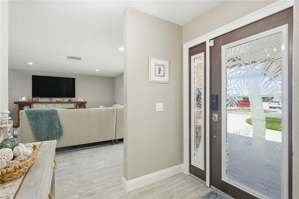 An entryway with a glass-paneled door leads into a living room with a sectional sofa — 5351 PILOTS PLACE, NEW PORT RICHEY, FL