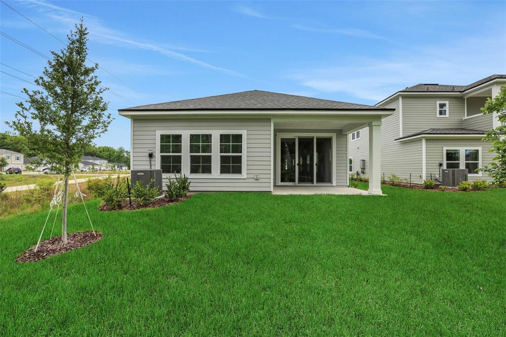 The rear exterior of a single-story house features gray siding, a covered patio, and lawn — 530 FARMFIELD DRIVE, ST AUGUSTINE, FL
