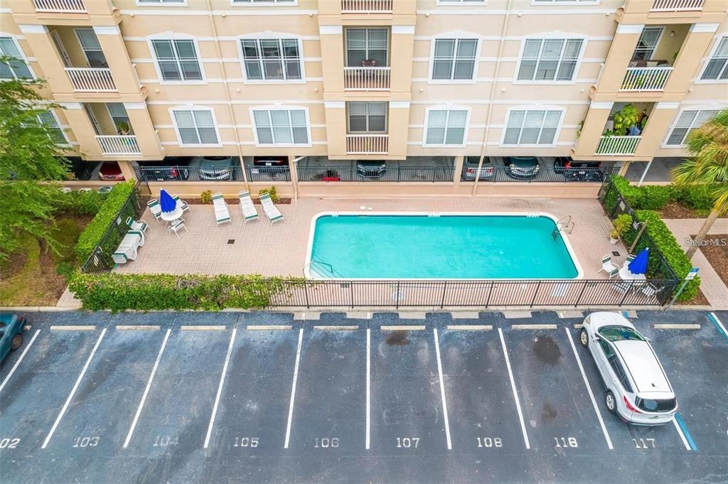 An aerial view shows a rectangular swimming pool, patio furniture, and numbered parking spaces — 1216 S MISSOURI AVENUE UNIT 317, CLEARWATER, FL