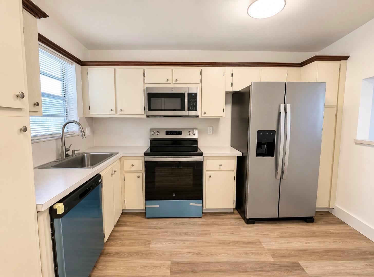 A kitchen features cream cabinets, stainless steel appliances, a sink, and light wood-look flooring — 601 S State Road 7 # 2h, Margate FL 33068, MARGATE, FL