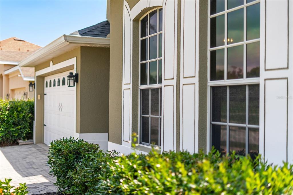 A side view of a house exterior featuring a garage, arched windows, and green landscaping — 478 SYCAMORE SPRINGS STREET, DEBARY, FL