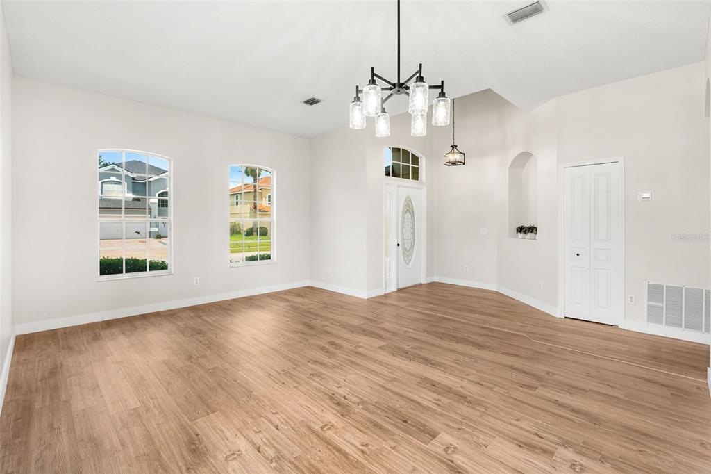 An empty room with light wood-look flooring, a chandelier, and a white front door — 478 SYCAMORE SPRINGS STREET, DEBARY, FL