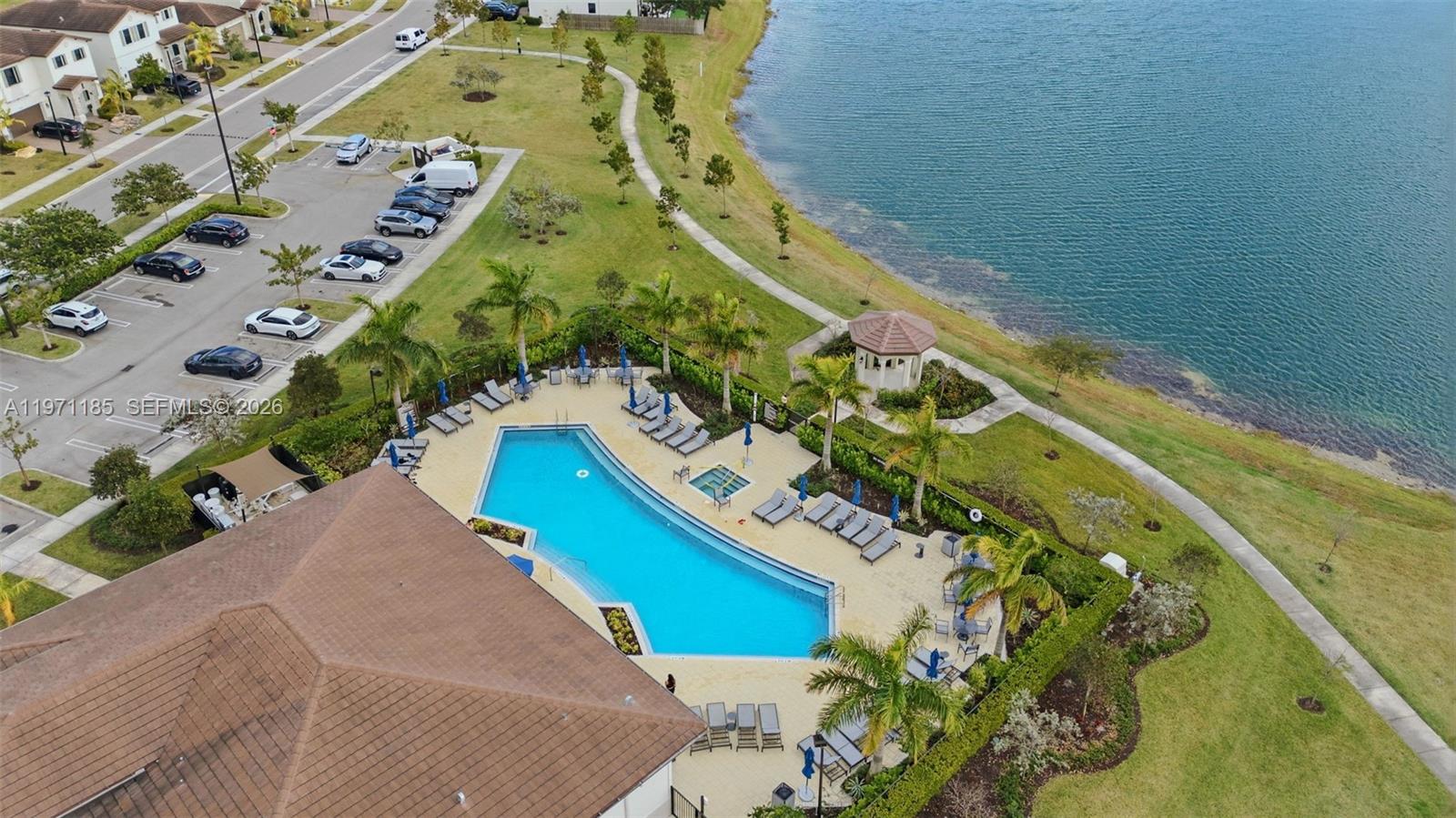 An aerial view shows a swimming pool, patio, and parking lot next to a lake — 10009 SW 228th Ter, Miami FL 33190, MIAMI, FL
