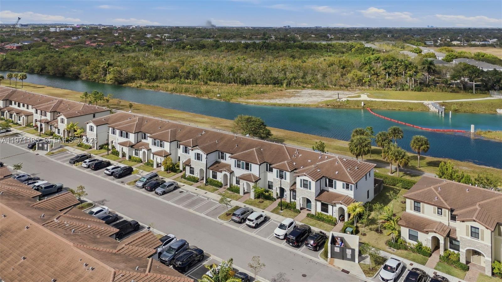An aerial view shows a row of townhouses with tiled roofs beside a canal — 10009 SW 228th Ter, Miami FL 33190, MIAMI, FL