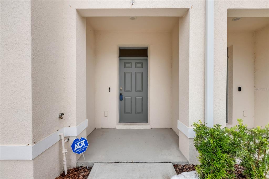The exterior entrance features a gray door, a concrete porch, and an ADT security sign — 148 REENA DRIVE, DAYTONA BEACH, FL