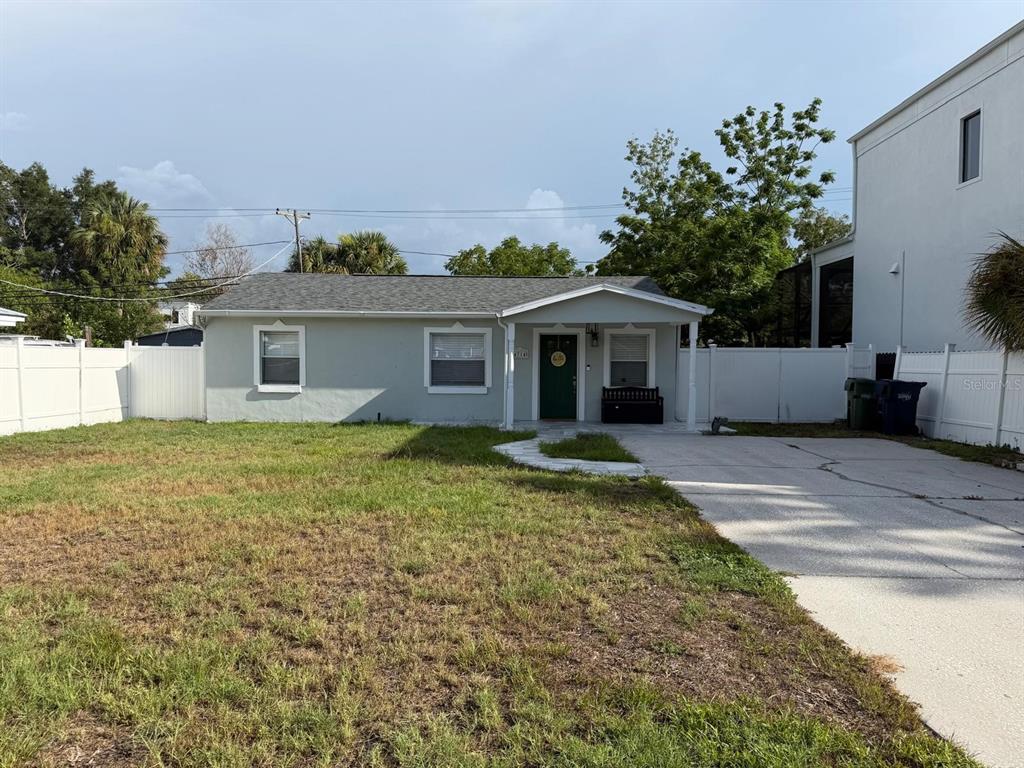 A single-story house with a light gray exterior, a green front door, and a concrete driveway — 4714 W LAWN AVENUE, TAMPA, FL