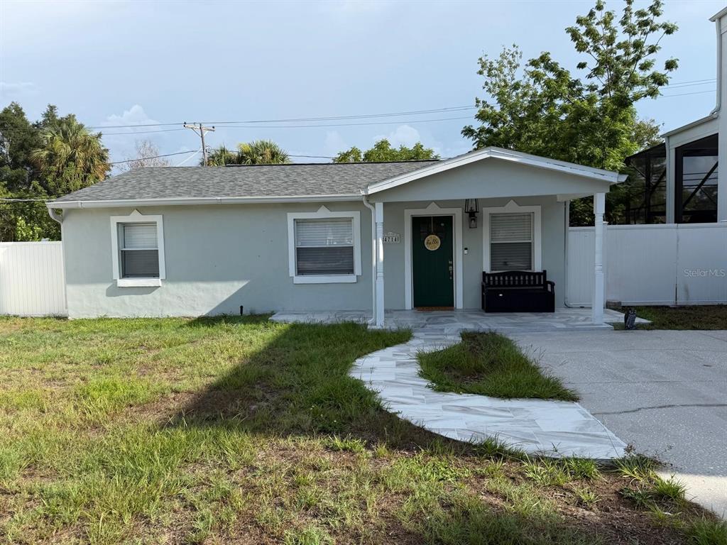 A single-story house with a light green exterior, a covered porch, and a tiled walkway — 4714 W LAWN AVENUE, TAMPA, FL