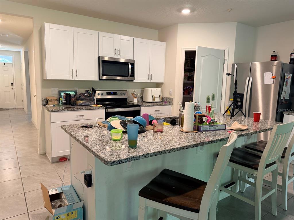 A kitchen features white cabinets, granite countertops, a center island, and stainless steel appliances — 507 LADY IRELYN COURT, DELAND, FL