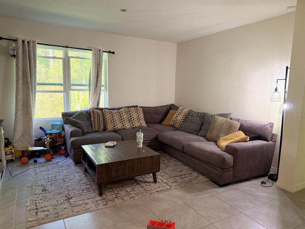 A living room features a large gray sectional sofa, a wooden coffee table, and tile flooring — 507 LADY IRELYN COURT, DELAND, FL
