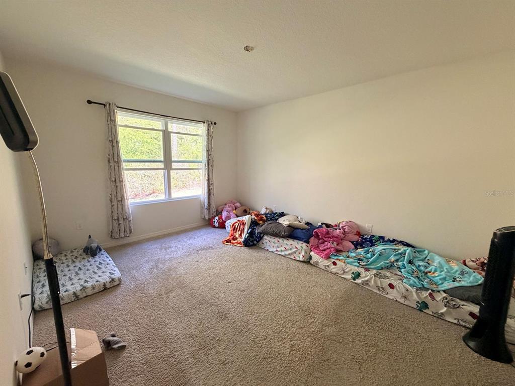 A bedroom with carpeted flooring features a single mattress and two joined mattresses on the floor — 507 LADY IRELYN COURT, DELAND, FL