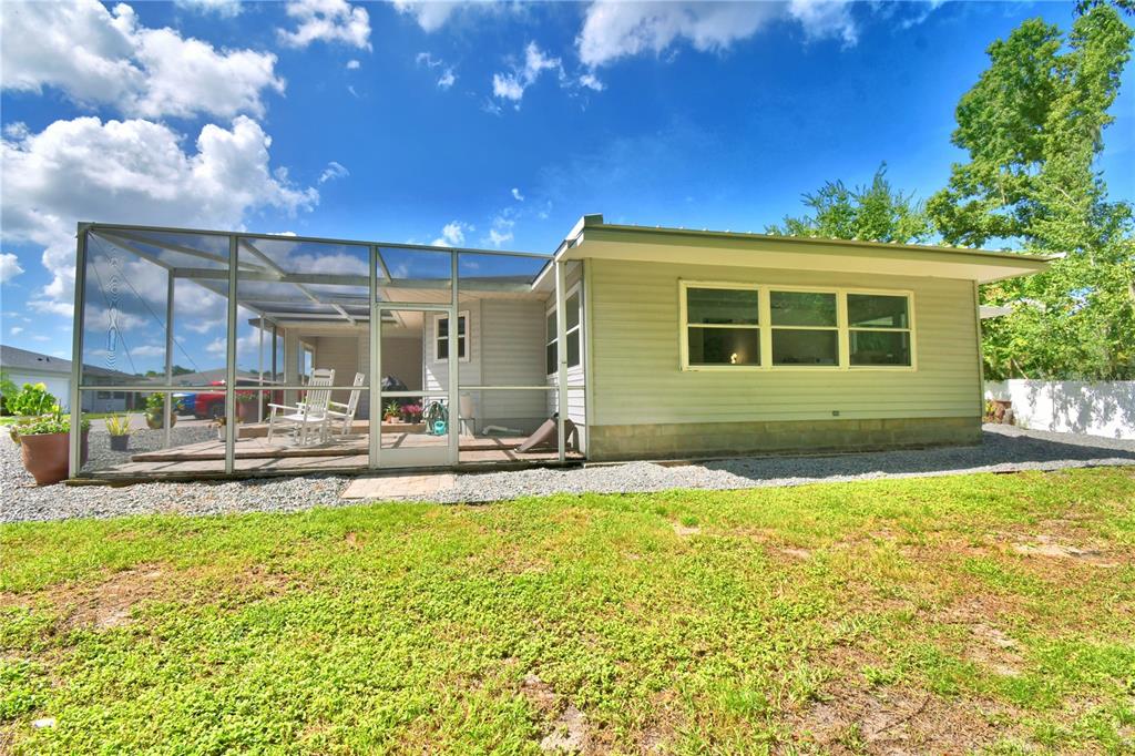 A light-colored house features a large screened-in porch and a gravel yard — 4789 SQUIRE HOLLOW DRIVE, LAKELAND, FL