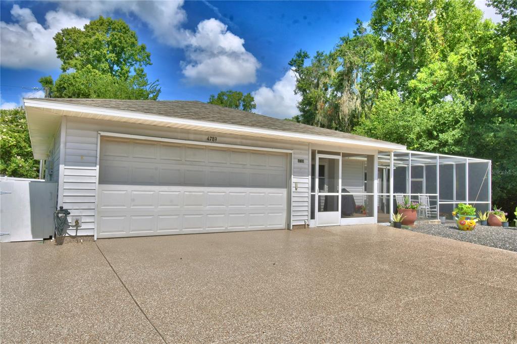 A white house with a two-car garage and a screened-in porch under a cloudy sky — 4789 SQUIRE HOLLOW DRIVE, LAKELAND, FL