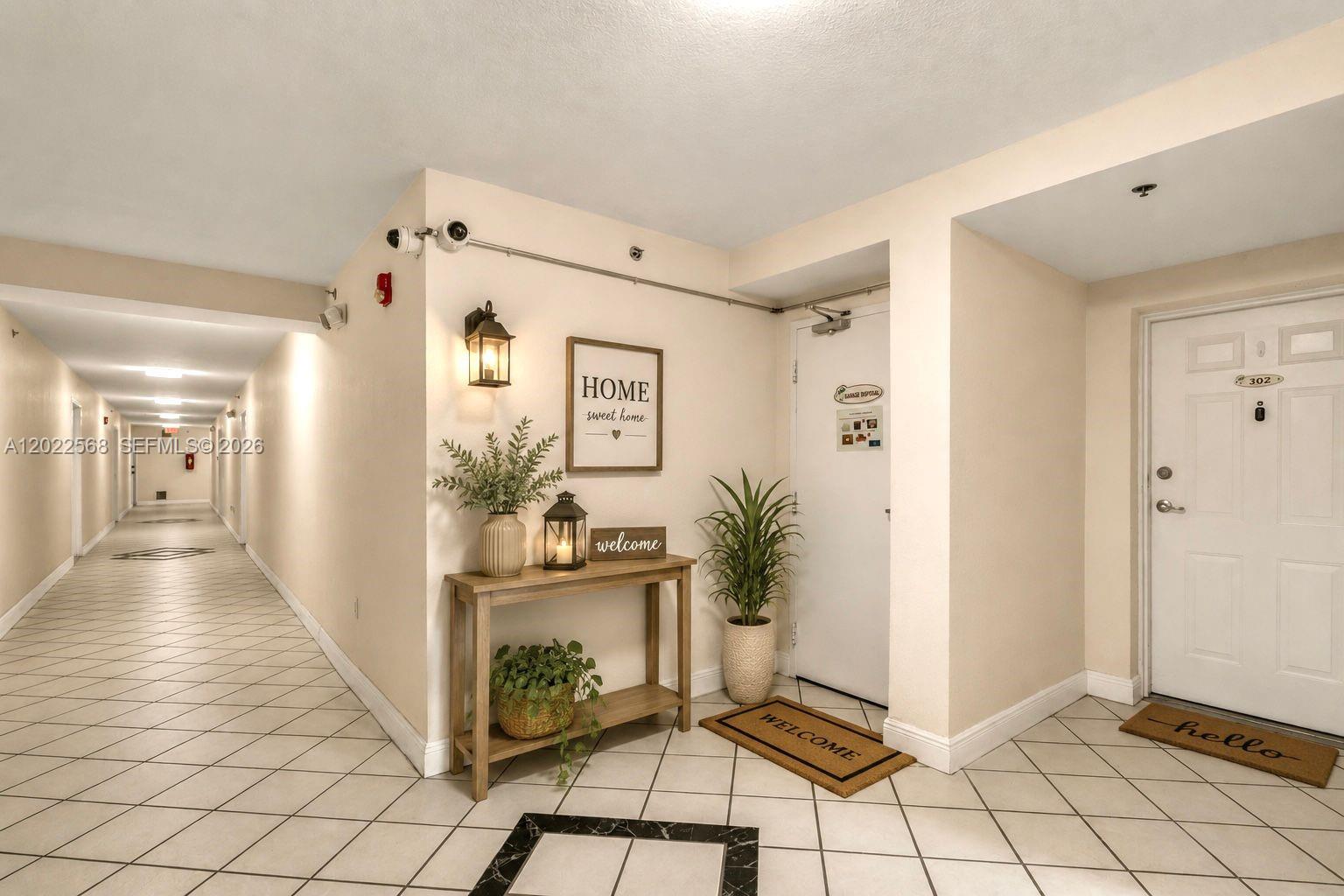 A hallway with tiled floors leads to a console table and a white apartment door — 814 NW 36th Ave # 302, Miami FL 33125, MIAMI, FL