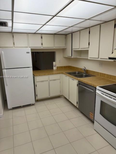A kitchen with white cabinets, a white refrigerator, a stainless dishwasher, and light-colored tile flooring — 400 Commodore Dr # 108, Plantation FL 33325, PLANTATION, FL