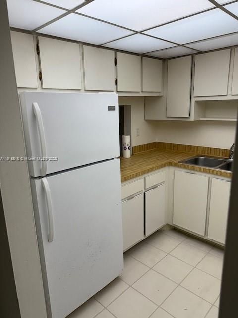 A kitchen features white cabinets, a white refrigerator, and a wood-look laminate countertop — 400 Commodore Dr # 108, Plantation FL 33325, PLANTATION, FL