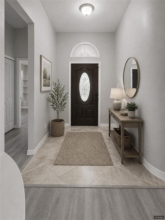 A bright entryway features a dark front door, tile flooring, a console table, and a mirror — 1810 GREYSTONE HEIGHTS DRIVE, VALRICO, FL