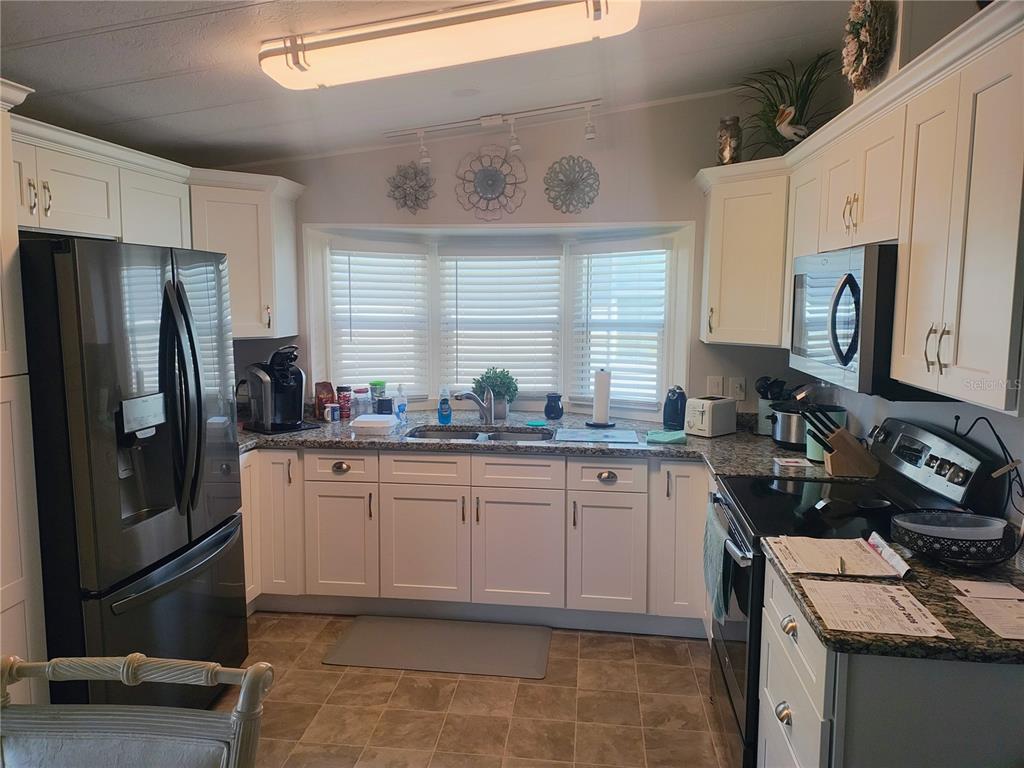 A kitchen features white cabinets, granite countertops, stainless steel appliances, and a bay window — 15550 BURNT STORE ROAD UNIT 236, PUNTA GORDA, FL