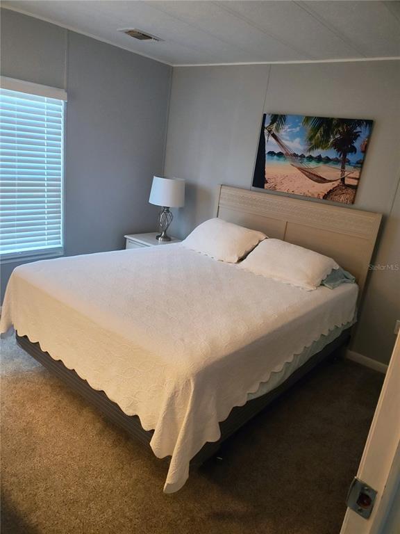 A bedroom features a bed with a white scalloped quilt, a nightstand, and wall art — 15550 BURNT STORE ROAD UNIT 236, PUNTA GORDA, FL