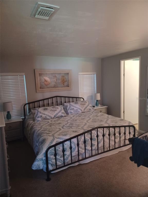 A bedroom features a metal bed frame, patterned bedding, two windows, and two nightstands — 15550 BURNT STORE ROAD UNIT 236, PUNTA GORDA, FL