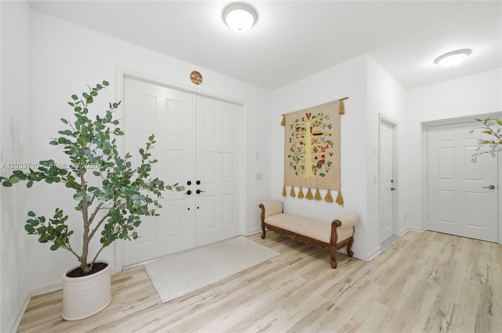 A bright entryway features double doors, light wood flooring, a decorative bench, and a wall tapestry — 2794 Kinsington Cir # 3, Weston FL 33332, WESTON, FL