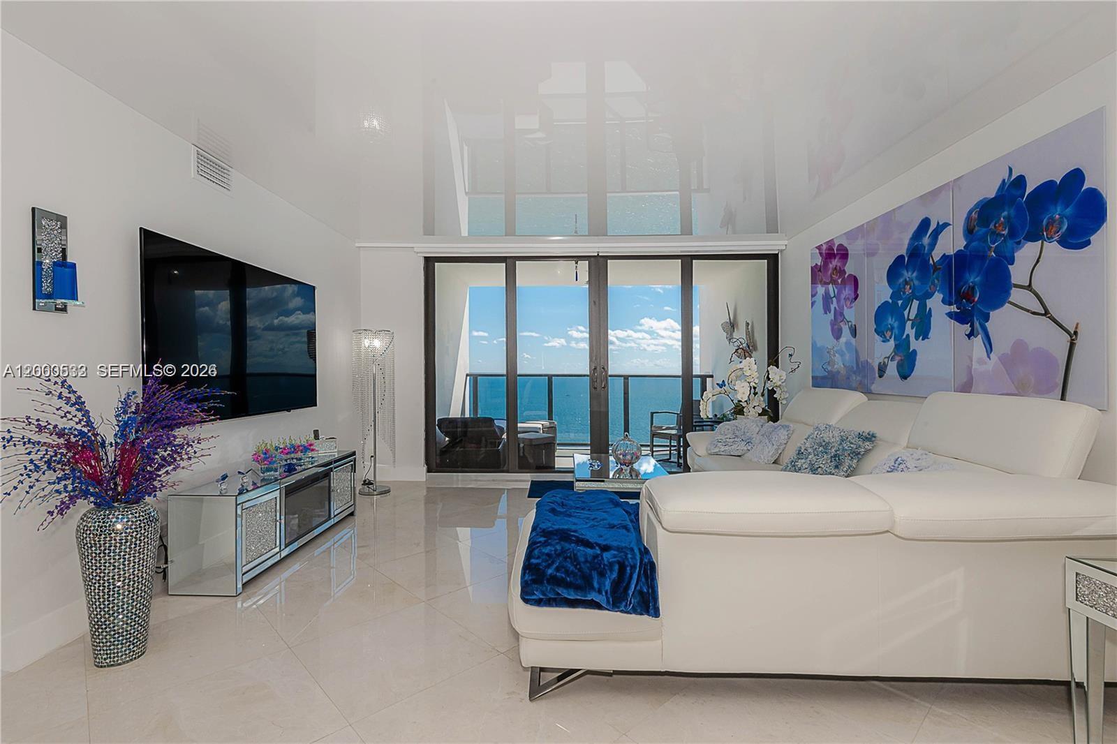 A modern living room features a white sectional sofa, mirrored media console, and ocean views — 2301 S Ocean Dr # 2003, Hollywood FL 33019, HOLLYWOOD, FL