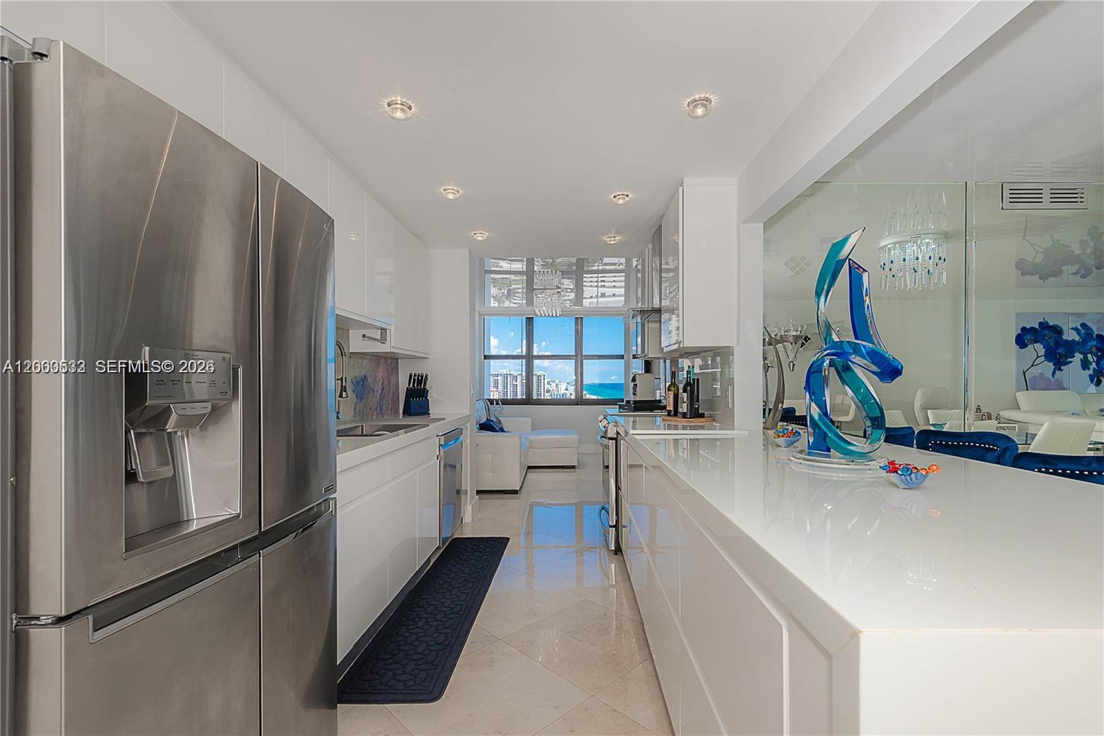 A modern white galley kitchen features stainless steel appliances and a view of the ocean — 2301 S Ocean Dr # 2003, Hollywood FL 33019, HOLLYWOOD, FL