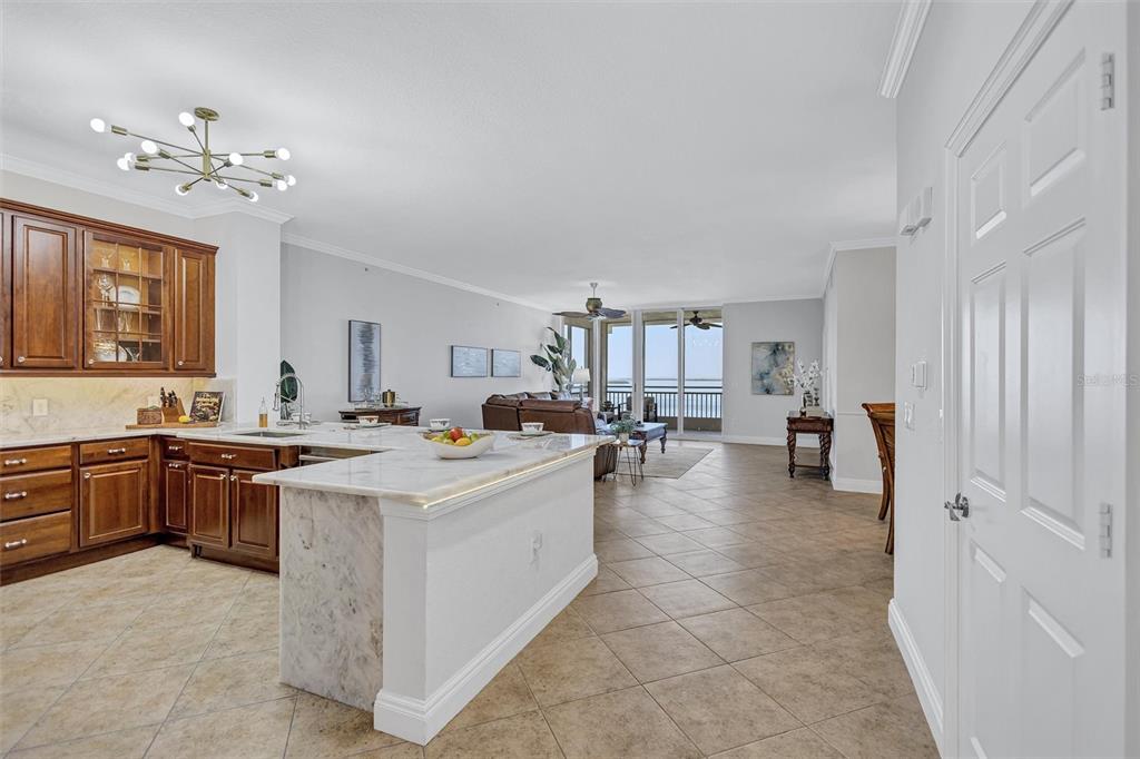 A kitchen with wood cabinets and a marble island opens into a living area with water views — 2925 TERRA CEIA BAY BOULEVARD UNIT 2802, PALMETTO, FL