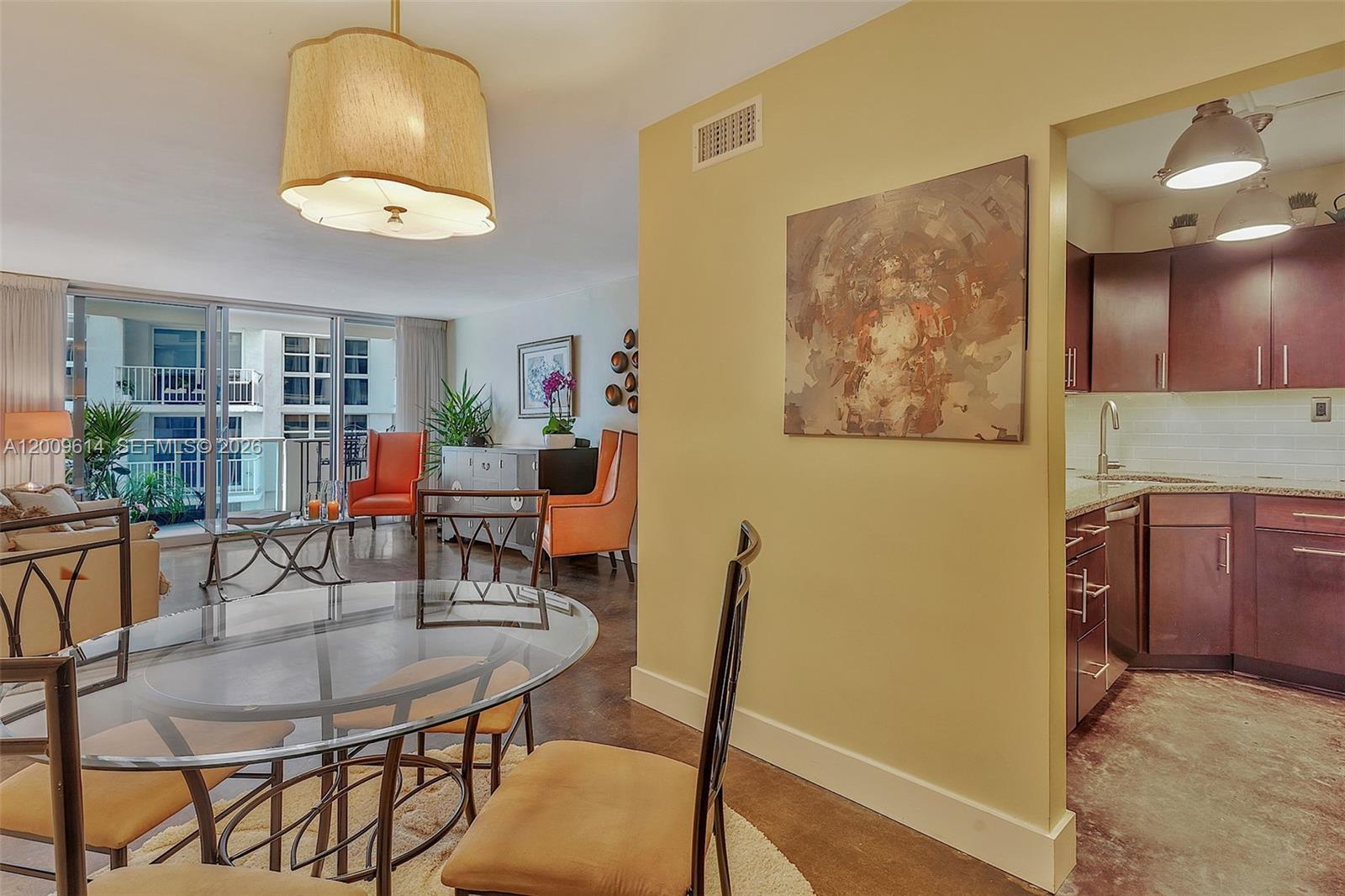 A dining area with a glass table sits beside a kitchen with dark wood cabinets — 1200 West Ave # 423, Miami Beach FL 33139, MIAMI BEACH, FL