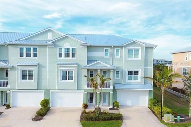 A light green multi-story townhouse complex with white garage doors and a metal roof — 10420 CORAL LANDINGS LANE UNIT 115, PLACIDA, FL