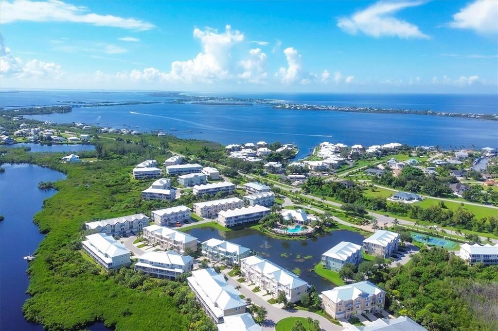 An aerial view shows a waterfront residential complex with white buildings surrounded by lush greenery — 10420 CORAL LANDINGS LANE UNIT 115, PLACIDA, FL
