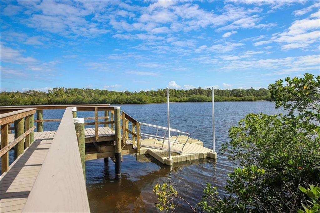 A wooden dock with a floating platform extends into a calm river bordered by mangroves — 10420 CORAL LANDINGS LANE UNIT 115, PLACIDA, FL